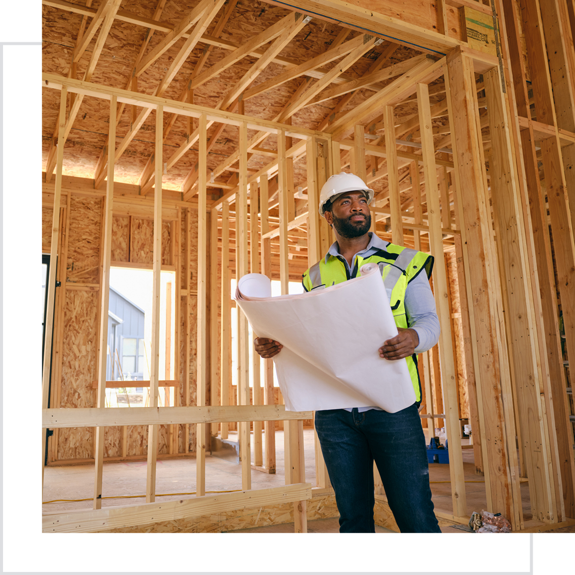 Construction worker examining building plans indoors.